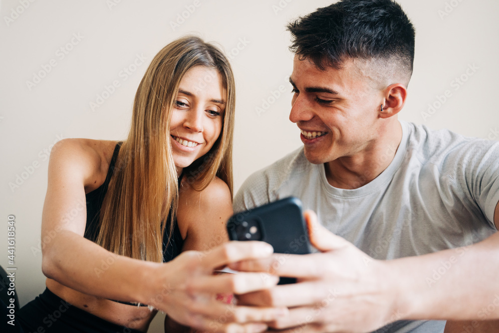 Cheerful couple browsing cellphone after training Cheerful couple browsing cellphone after training