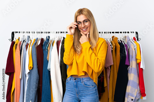 Young Uruguayan blonde woman in a clothing store with glasses and smiling