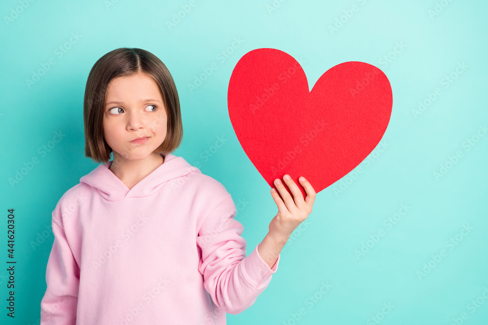 Photo of brunette hairdo unsure little girl hold look paper heart wear pink sportswear isolated on teal color background Photo of brunette hairdo unsure little girl hold look paper heart wear pink sportswear isolated on teal color background