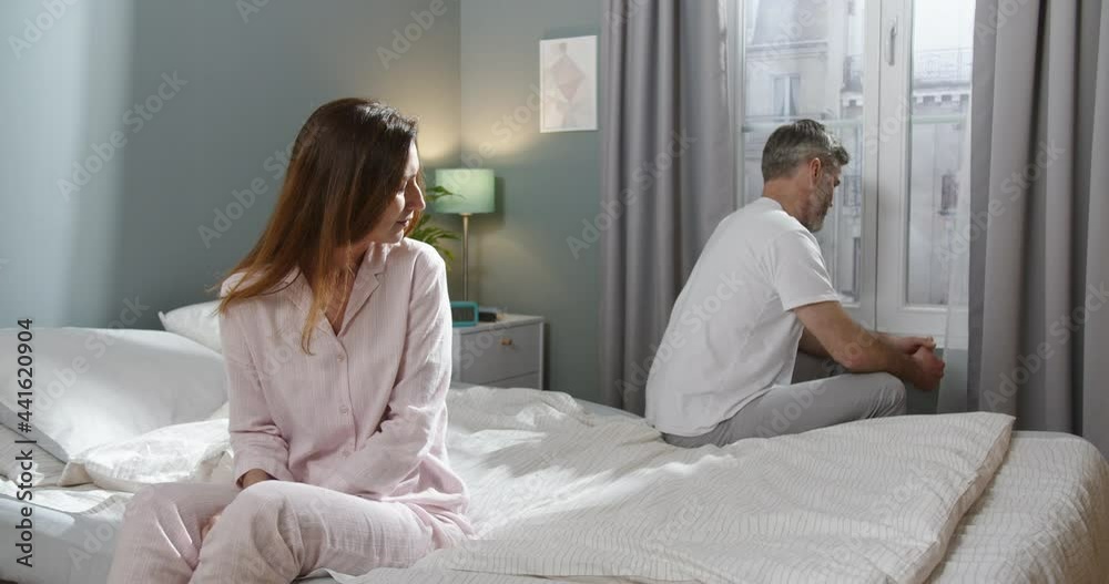 Angry unhappy adult couple ignoring and not looking at each other after family fight or quarrel. Upset thoughtful spouses avoiding talk, sitting silently at the bed, while having relationship troubles Angry unhappy adult couple ignoring and not looking at each other after family fight or quarrel. Upset thoughtful spouses avoiding talk, sitting silently at the bed, while having relationship troubles
