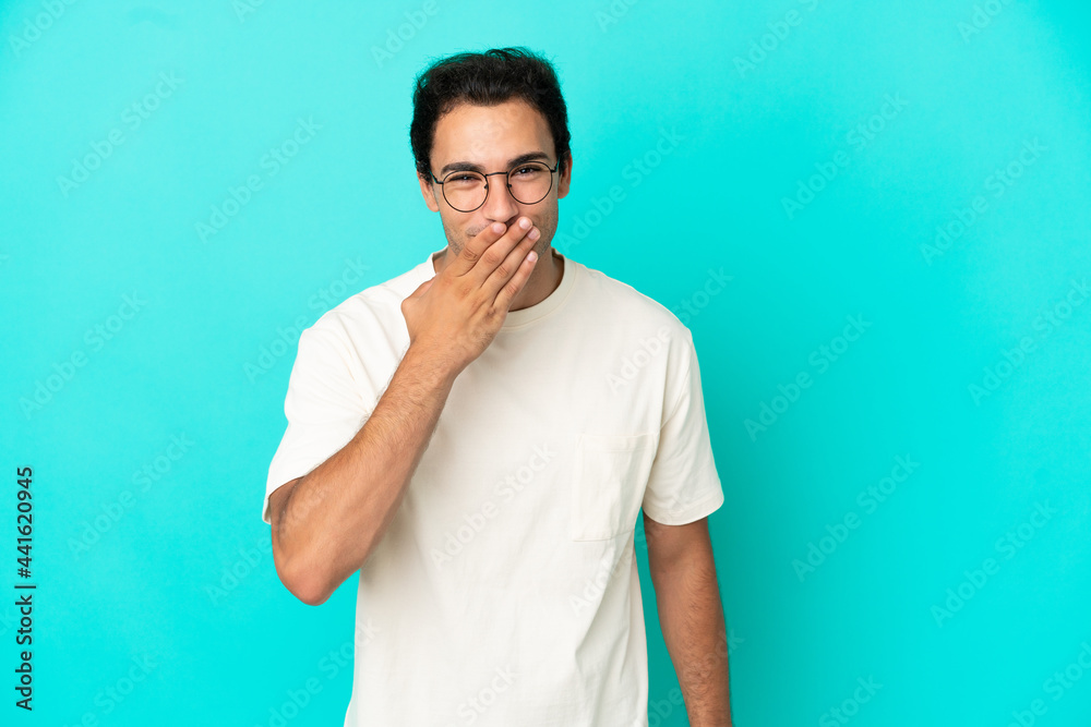 Caucasian handsome man over isolated blue background happy and smiling covering mouth with hand Caucasian handsome man over isolated blue background happy and smiling covering mouth with hand