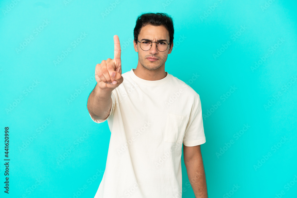 Caucasian handsome man over isolated blue background counting one with serious expression Caucasian handsome man over isolated blue background counting one with serious expression