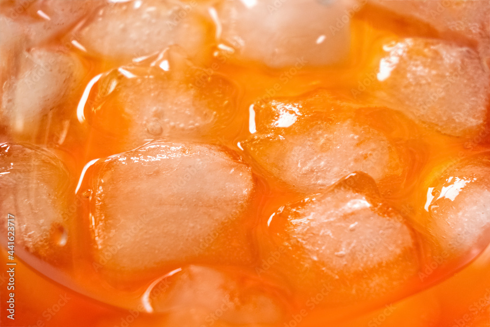 Ice cubes melt in glass with aperol spriz cocktail, close up Ice cubes melt in glass with aperol spriz cocktail, close up