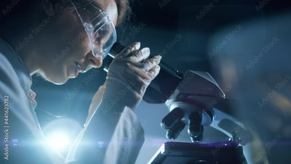 A woman scientist is looking into microscope, biochemical research. Scientific and medical lab instrument. A doctor is search for vaccine to treat diseases in laboratory for medicine study