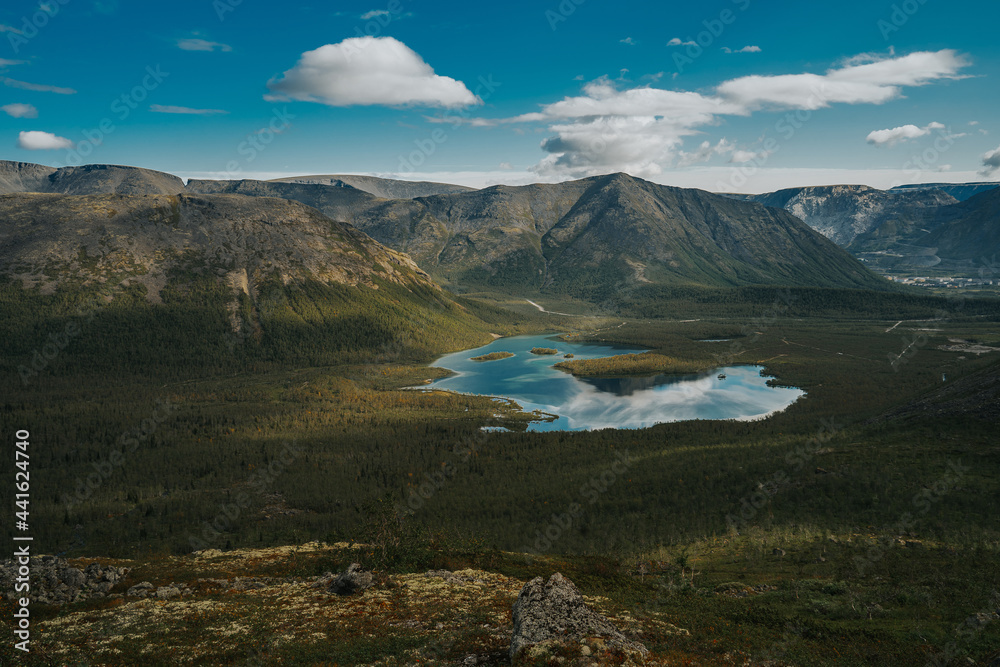 Beautiful blue lake with a reflection of the sky in valley on the background mountain picks  in cloudy weather in polar summer, top view. Arctic, Kola Peninsula 