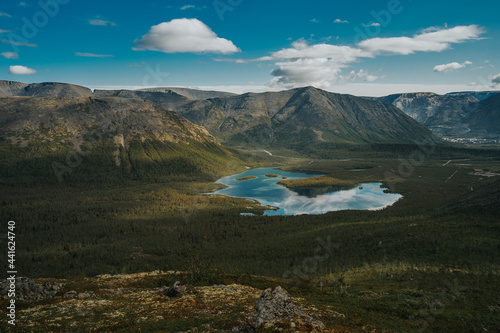 Beautiful blue lake with a reflection of the sky in valley on the background mountain picks in cloudy weather in polar summer, top view. Arctic, Kola Peninsula 