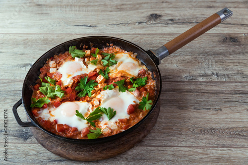 Shakshuka in a frying pan, poached eggs in spicy tomato sauce. Summer breakfast with eggs and tomato sauce.