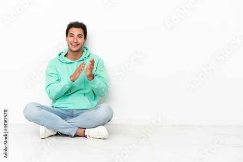 Caucasian handsome man sitting on the floor applauding after presentation in a conference