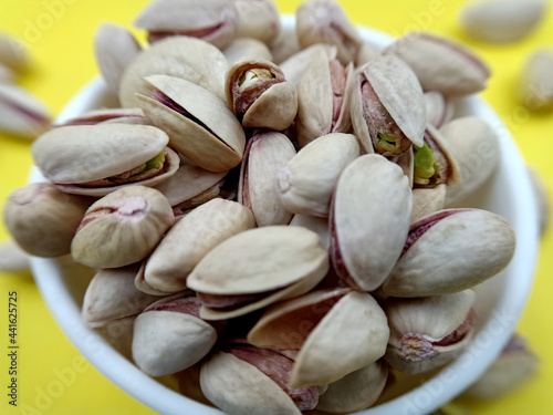 pistachio nuts in a bowl on yellow background