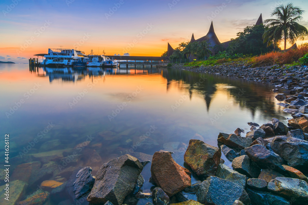 Enjoy the sunrise at the marina port with traditional houses and rocks as the background