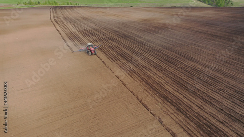 Aerial view of the tractor in the field, agricultural field work, sowing work in the field at sunset