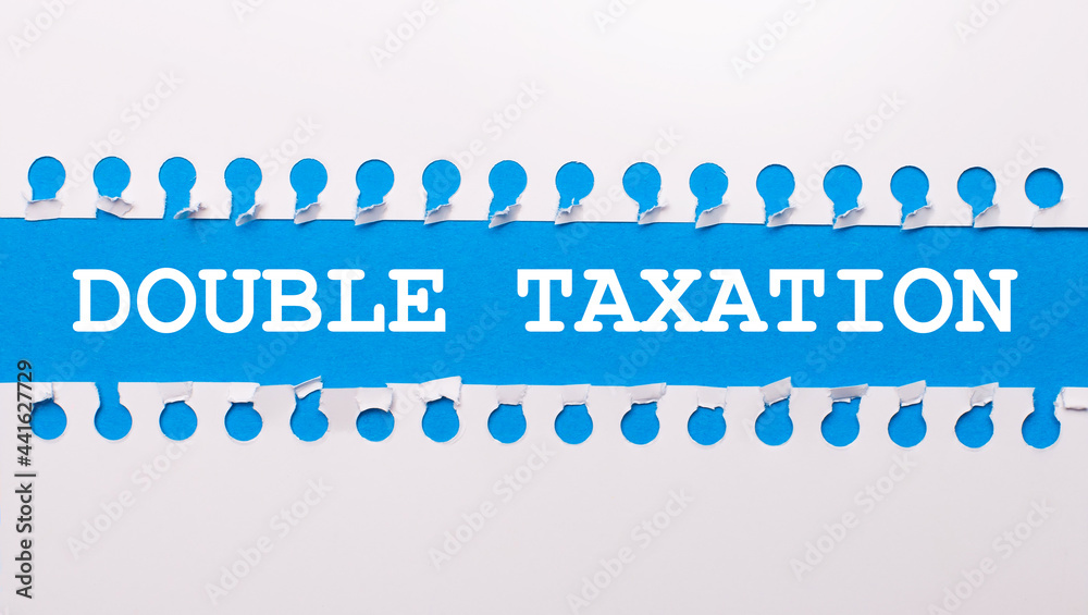 On a blue background with text DOUBLE TAXATION two white torn strips of paper.