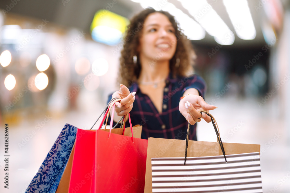 Close up of a woman's hand holding shopping bags. Young woman after shopping in the mall. Consumerism, sale, purchases, lifestyle concept. Close up of a woman's hand holding shopping bags. Young woman after shopping in the mall. Consumerism, sale, purchases, lifestyle concept.