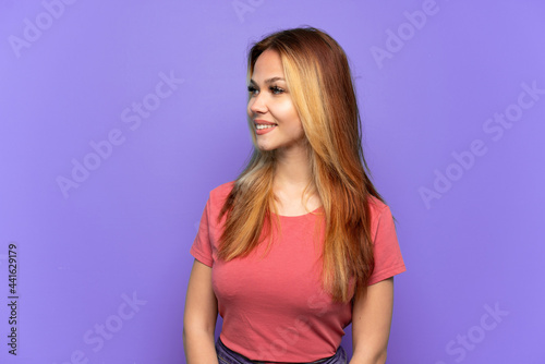 Teenager girl over isolated purple background looking side