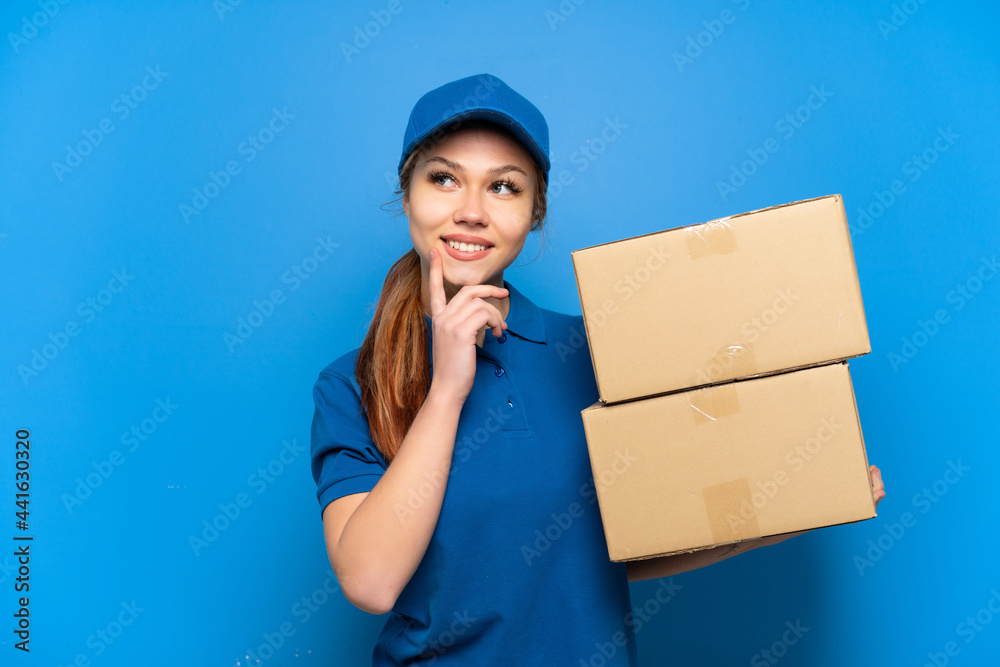 Delivery girl over isolated blue wall thinking an idea while looking up Delivery girl over isolated blue wall thinking an idea while looking up