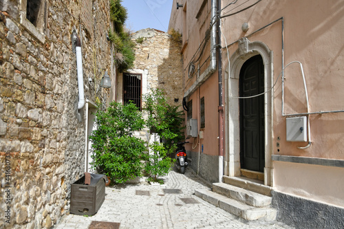 Fototapeta Naklejka Na Ścianę i Meble -  Candela, Italy, 06/21/2021. A small street between the old houses of a mediterranean village of Puglia region.