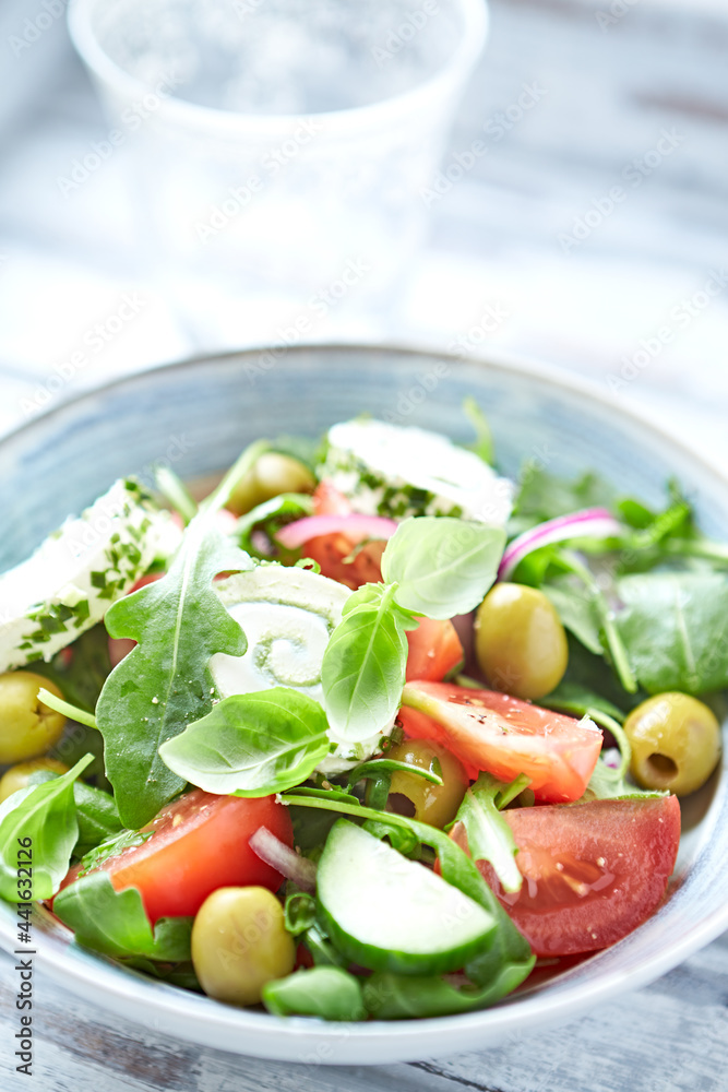 Summer Salad with Cream Cheese, green Olives, Tomatoes and fresh Basil. Bright wooden background. Close up. 