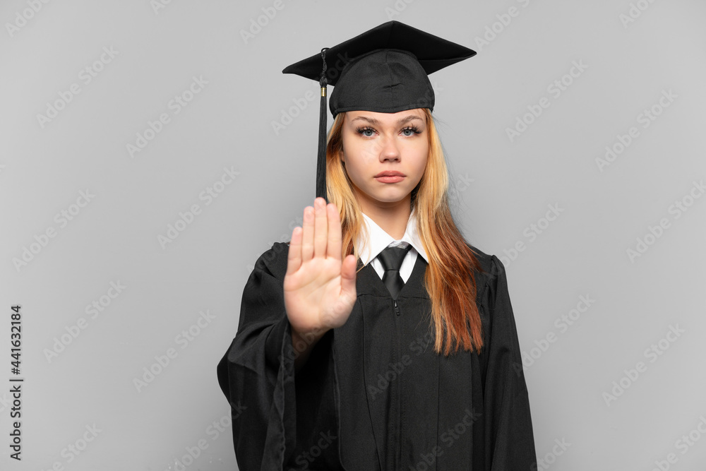 Young university graduate girl over isolated background making stop gesture