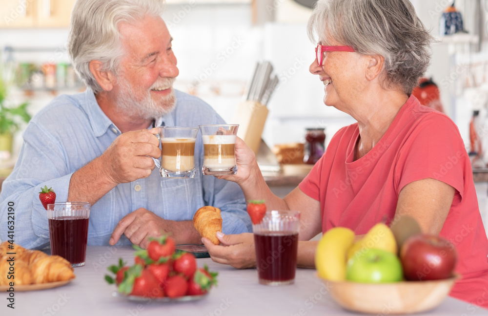 Caucasian couple having breakfast at home. Senior people relaxed and happy, holding a coffee and milk cup Caucasian couple having breakfast at home. Senior people relaxed and happy, holding a coffee and milk cup