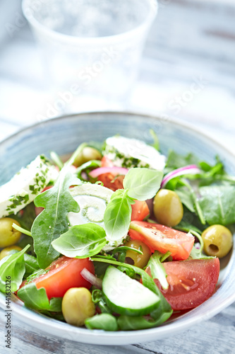 Summer Salad with Cream Cheese, green Olives, Tomatoes and fresh Basil. Bright wooden background. Close up. 