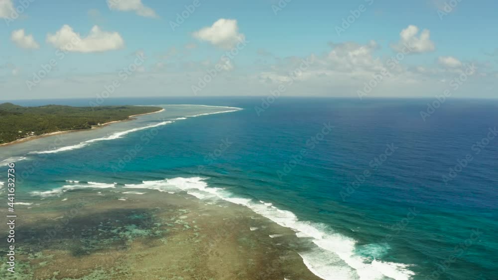 The coast of Siargao island with beach, green forest and ocean surf with waves against the sky and clouds, aerial view. tropical landscape. The coast of Siargao island with beach, green forest and ocean surf with waves against the sky and clouds, aerial view. tropical landscape.