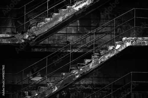 Old concrete staircase with rusty railing in black and white.