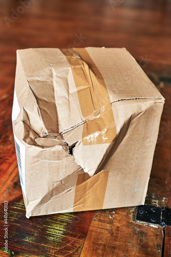 Cardboard package that was damaged in shipping and has a crack and dents.