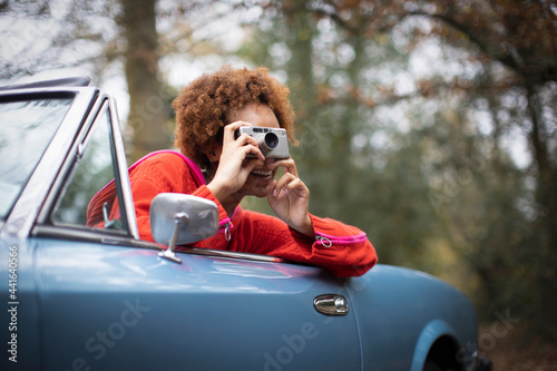 Young woman using digital camera in convertible