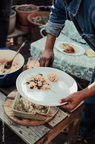 Person serving rice on a plate at outdoor dinner party