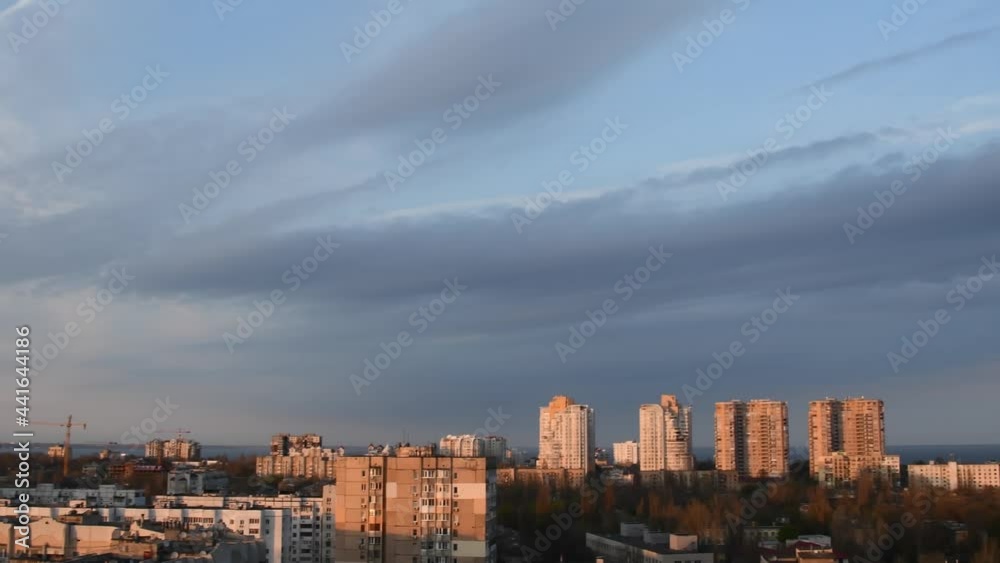 Pan aerial view of urban skyline with spindrift clouds in blue sky while golden hour of sunset. Cityscape of high-rise buildings at waterfront and sea on horizon Pan aerial view of urban skyline with spindrift clouds in blue sky while golden hour of sunset. Cityscape of high-rise buildings at waterfront and sea on horizon