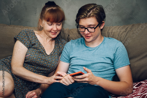 Home photo teen son listens to mom sitting on the sofa right in front of the camera