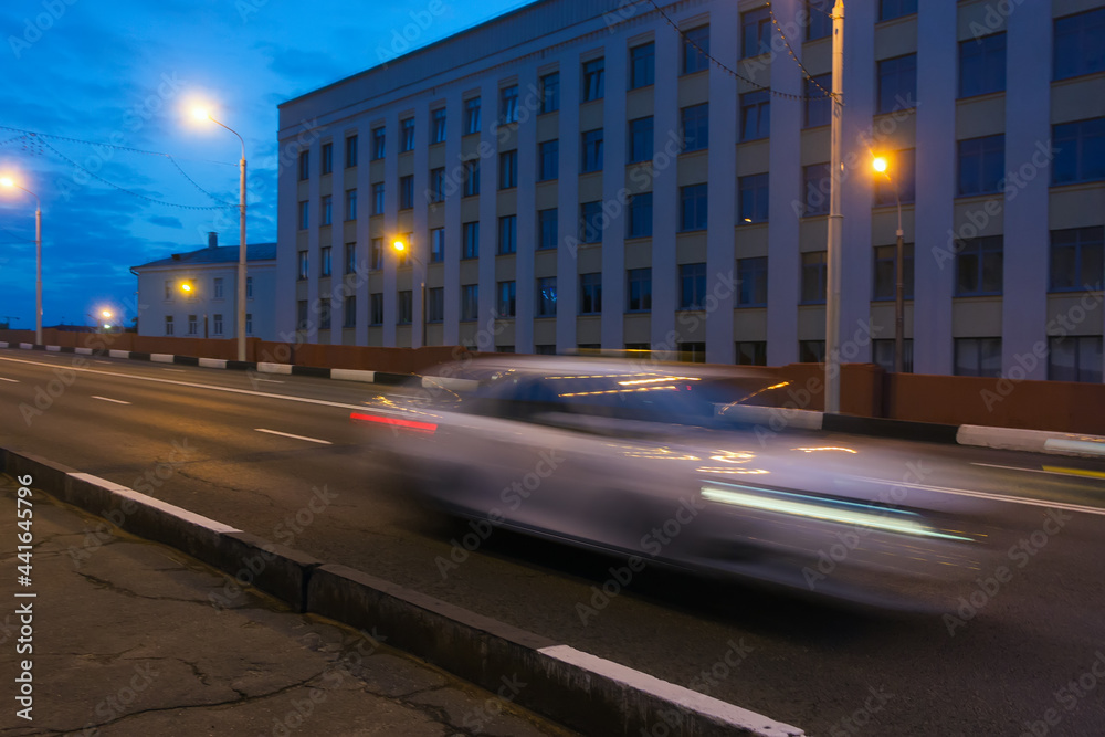 Fototapeta premium Motion of a blurred car along the overpass in the evening.
