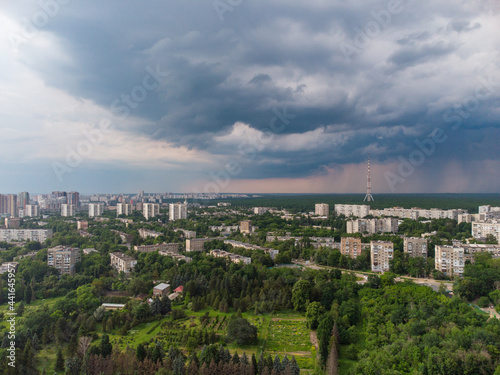 Aerial view on green Kharkiv city center Botanical garden and Pavlove Pole. Multistory buildings with telecommunication tower antenna with scenic rainy dark heavy clouds sky