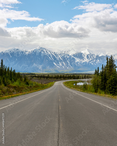 Haines Highway, Yukon Territory with huge snow capped peaks and clouds with blue sky. 
