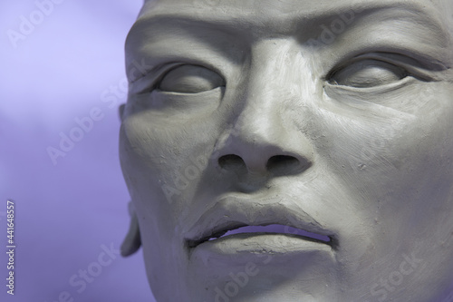 Face detail. Clay Sculpture in process of creation, Asian features, on lilac background.