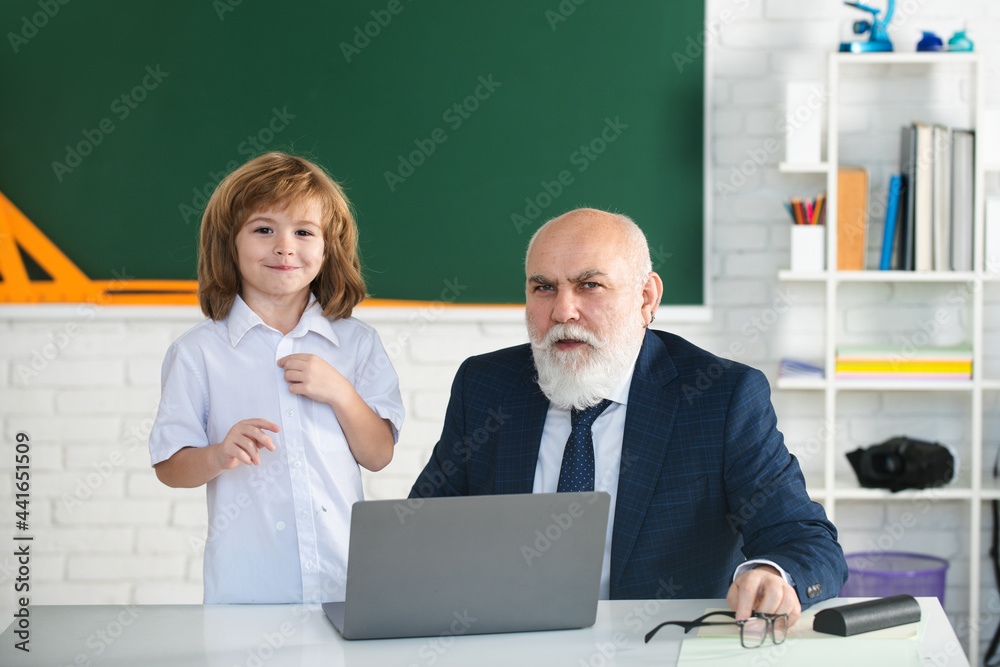 Teacher with schoolboy in classroom. Pupil with laptop. Education and learning. Teacher help to learn. Happy lessons. Back to school. Teacher with schoolboy in classroom. Pupil with laptop. Education and learning. Teacher help to learn. Happy lessons. Back to school.