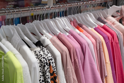 NEW Multicolored new Winter sport sweaters on hangers in a sports clothes store. Row of different, women long sleeve shirts. fleece jackets selling