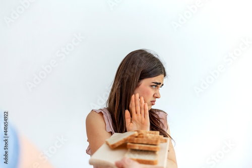 Woman refusing plate of white bread offered by a person. Gluten intolerance and diet concept. Woman refuses to eat white bread. Selective focus. Unhappy woman  rejecting to eat bread. Copy space.