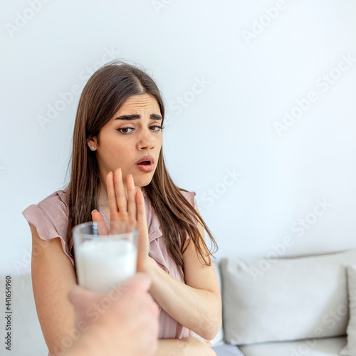 Lactose intolerance. Dairy Intolerant young girl refuses to drink milk - shallow depth of field. Selective focus. Girl having milk allergy. Lactose intolerance concept. Woman having milk allergy.