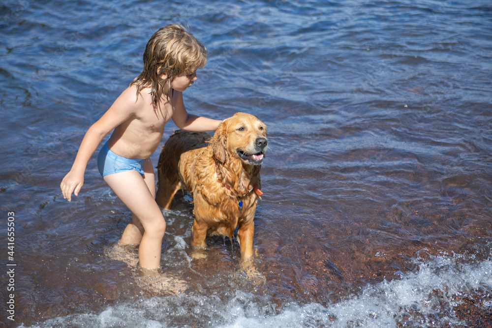 Child playing with dog in sea water on beach.