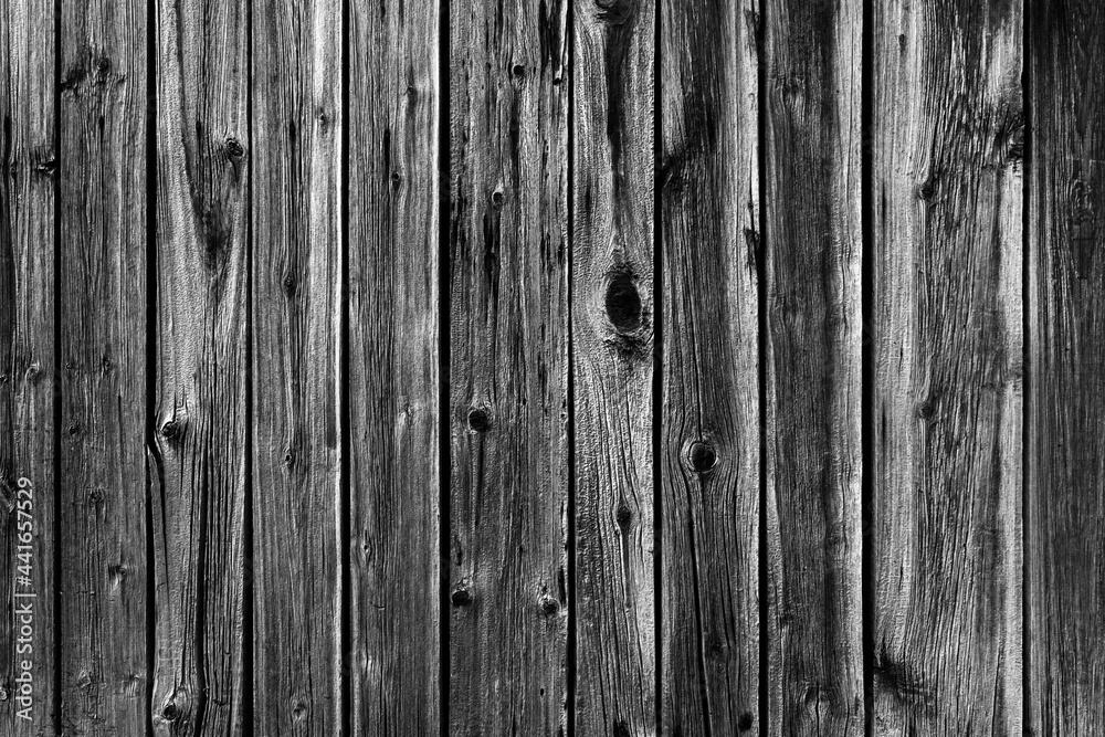Black and white background photo of an old worn wooden fence made of planks. Black and white background photo of an old worn wooden fence made of planks.