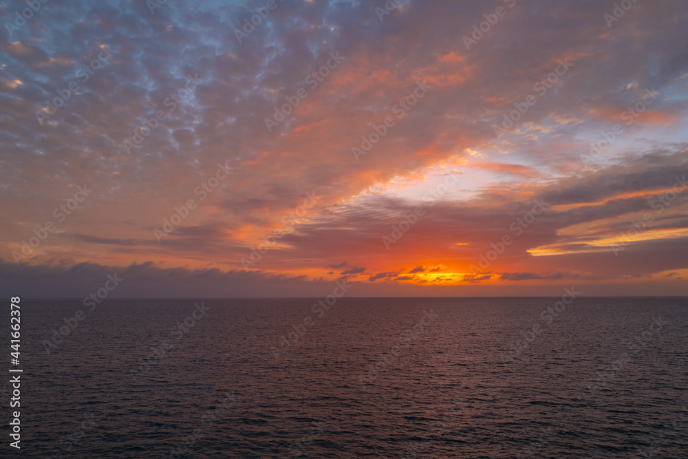 Obraz premium Calm sea with sunset sky and sun through the clouds over. Ocean and sky background, seascape.