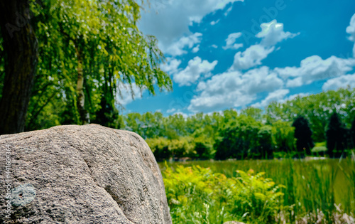 A huge stone ans rock and behind green public, nature park in Bursa during sunny day. Park with small pond behind green grass and fresh trees in spring time with blue sky and white clouds in day time 