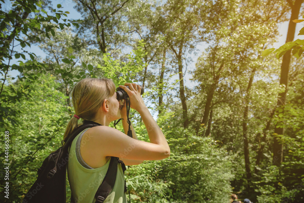 Obraz premium Young woman bird watching with binoculars at Indiana Dunes State Park