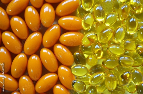 Two types of dietary supplements in yellow and orange capsules. photo