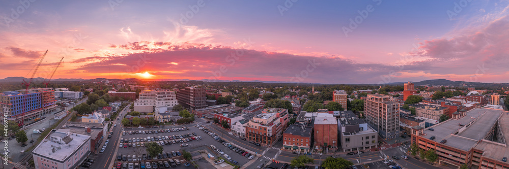 Aerial sunset view of downtown Charlottesville, Virginia with new construction office apartment building, city market parking lot, parking garage and the mall with dramatic colorful purple orange sky