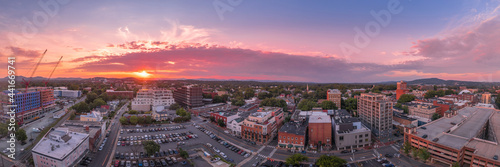 Aerial sunset view of downtown Charlottesville, Virginia with new construction office apartment building, city market parking lot, parking garage and the mall with dramatic colorful purple orange sky 