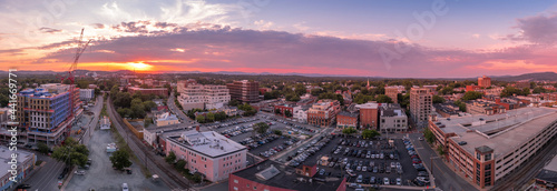 Aerial sunset view of downtown Charlottesville, Virginia with new construction office apartment building, city market parking lot, parking garage and the mall with dramatic colorful purple orange sky  photo