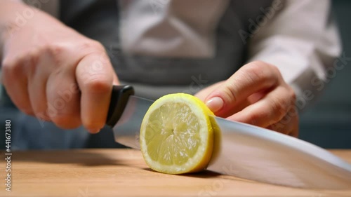 Female hands cut juicy lemon in round slices. Close up