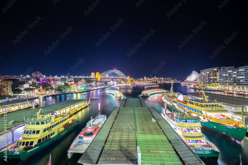 Panoramic night view of Sydney Harbour and City Skyline of circular quay the bridge  nsw Australia.  bright neon lights reflecting off the water